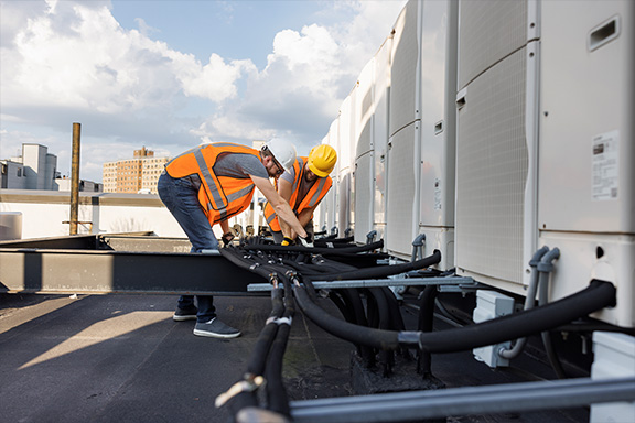 Engineers managing cables behind an AHU